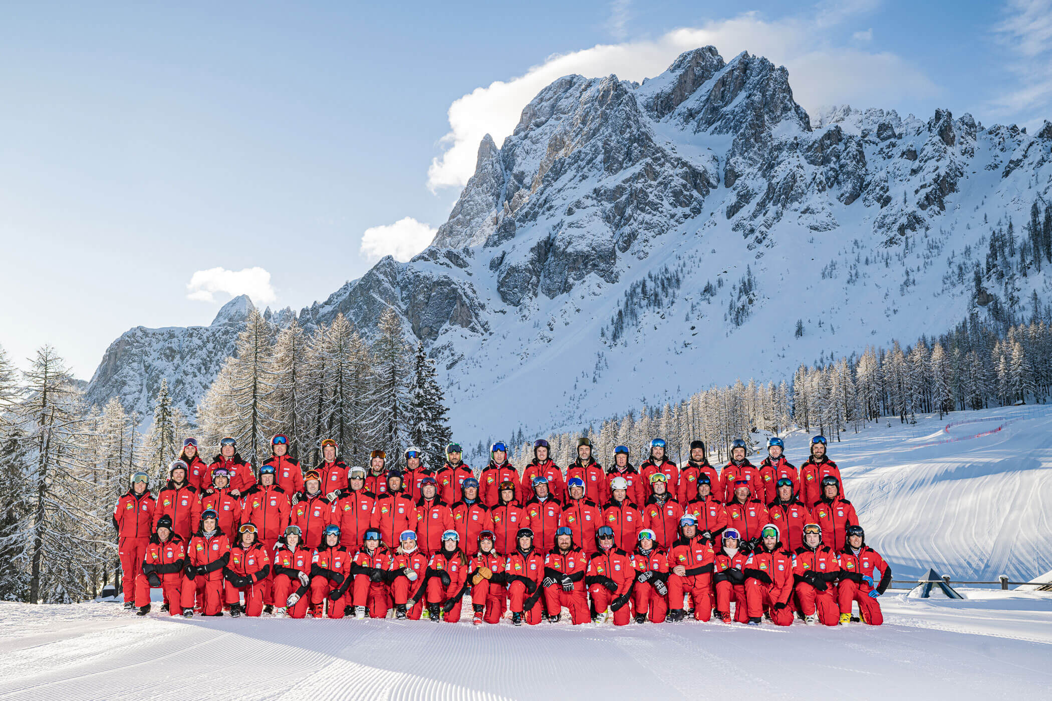 Alle Mitglieder und Mitarbeiter vor einem verschneiten Berge - SkiSchule Sexten